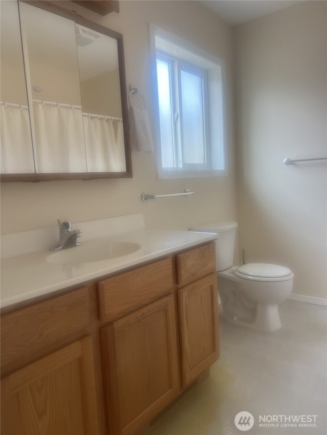 bathroom with vanity, baseboards, and toilet