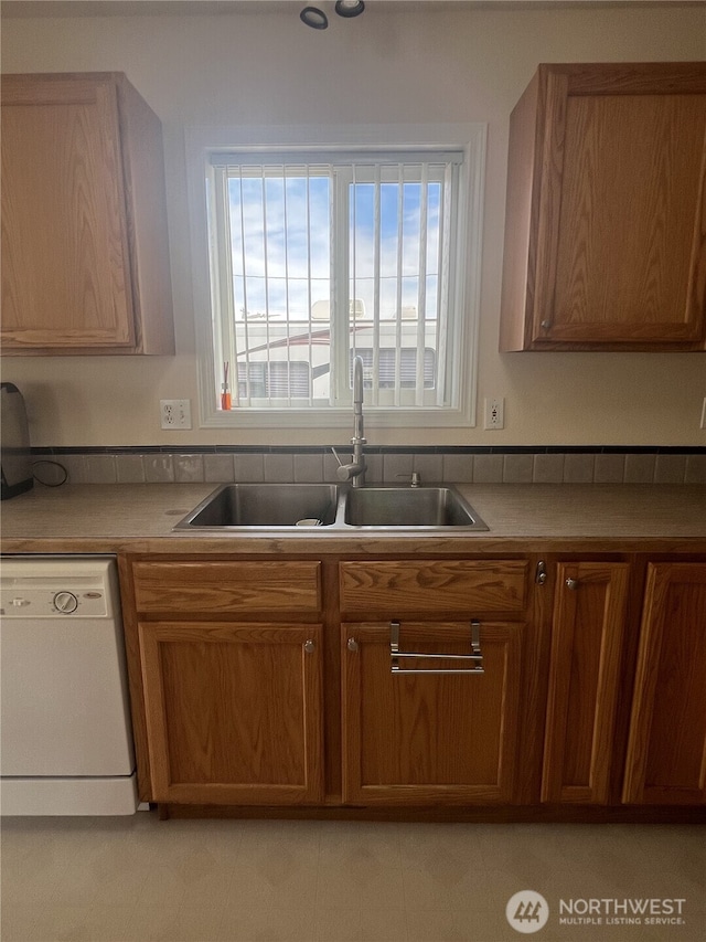 kitchen featuring brown cabinetry, a sink, and dishwasher