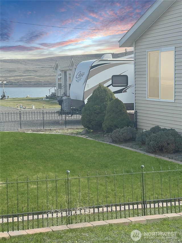 view of yard with a fenced backyard and a water view
