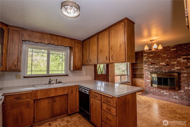 kitchen with brown cabinets, light countertops, a sink, a peninsula, and black dishwasher