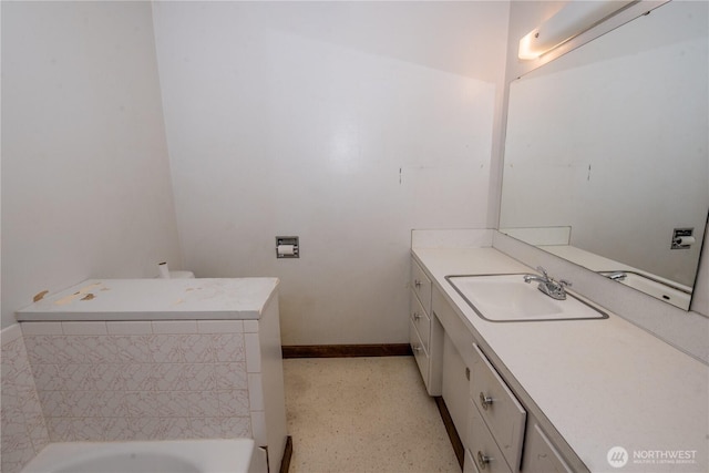 bathroom featuring washer / dryer, baseboards, vanity, and a bathing tub