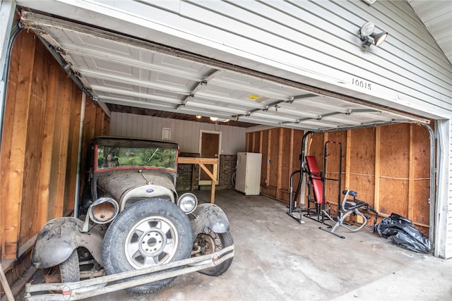garage with freestanding refrigerator and wood walls