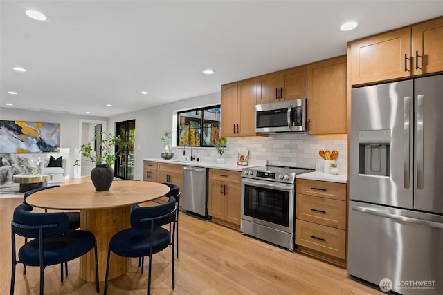 11016 46th St E, Edgewood, WA 98372 - kitchen featuring appliances with stainless steel finishes, light wood-style floors, light countertops, tasteful backsplash, and recessed lighting