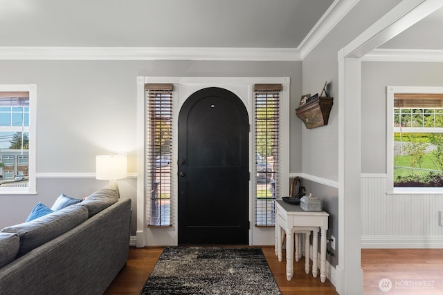foyer with ornamental molding, wainscoting, and wood finished floors