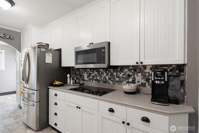 kitchen with white cabinets, stainless steel appliances, arched walkways, and tasteful backsplash