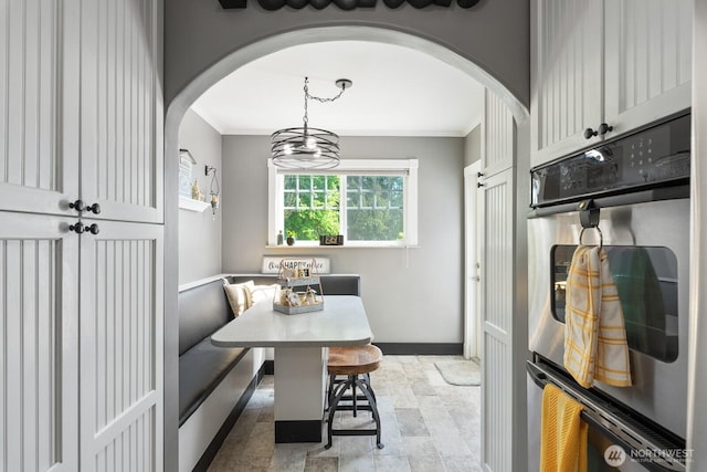 dining space featuring crown molding, arched walkways, and breakfast area