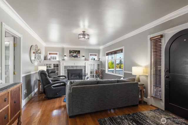 living room with baseboards, ornamental molding, dark wood finished floors, and a glass covered fireplace