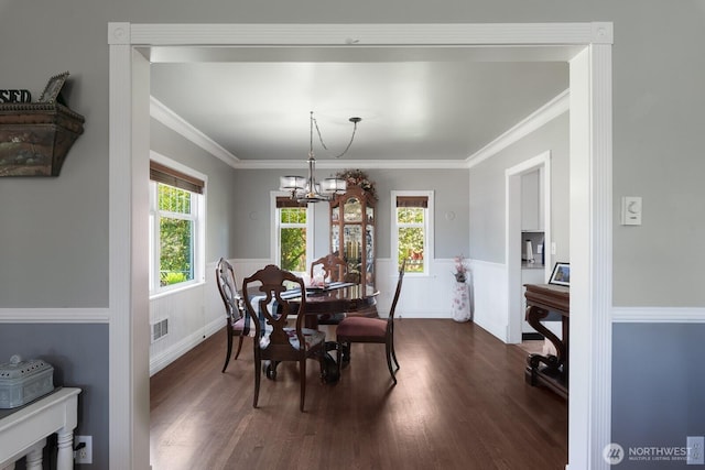 dining area with a wainscoted wall, dark wood-style floors, a chandelier, and visible vents