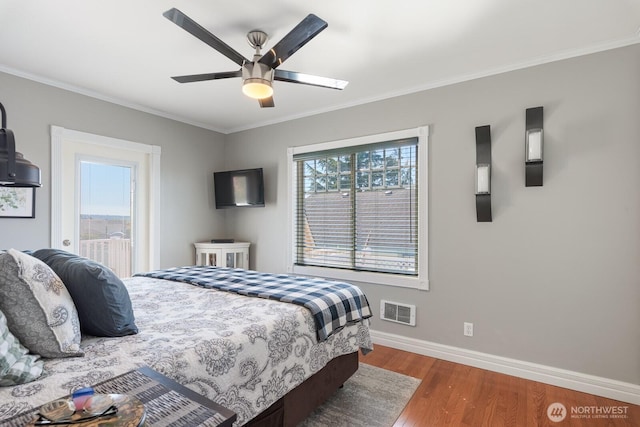 bedroom featuring crown molding, a ceiling fan, baseboards, wood finished floors, and visible vents
