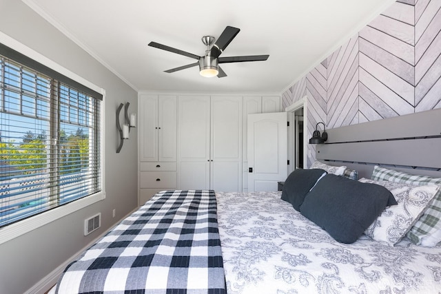 bedroom with a closet, ornamental molding, a ceiling fan, and visible vents