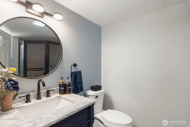 bathroom with toilet, a shower stall, and vanity