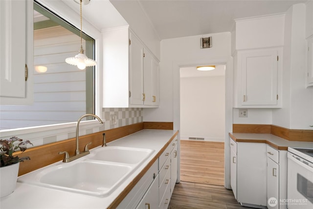 kitchen with dark wood finished floors, decorative light fixtures, electric range, white cabinets, and a sink