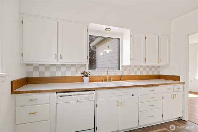 kitchen with white cabinetry, dishwasher, light countertops, and a sink