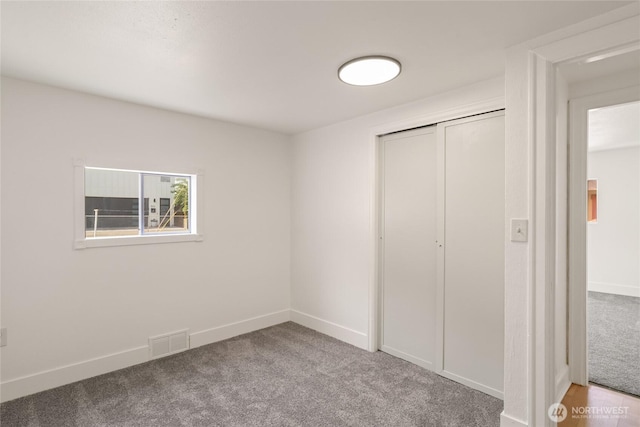 unfurnished bedroom with visible vents, a closet, carpet flooring, and baseboards