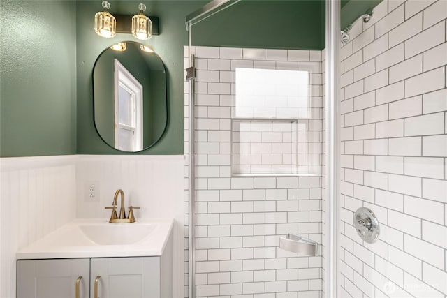 bathroom featuring wainscoting, tiled shower, and vanity