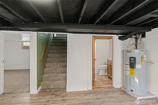 below grade area with stairway, wood finished floors, and electric water heater