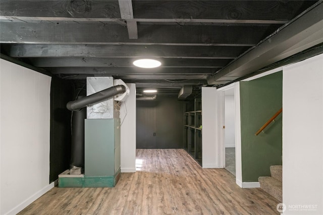finished below grade area featuring baseboards, stairway, and wood finished floors