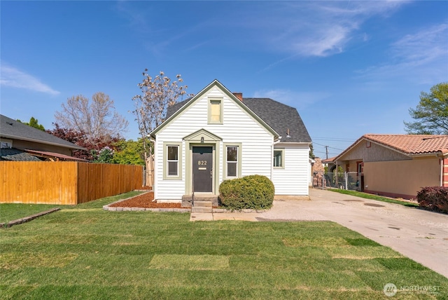 bungalow featuring a front yard, driveway, entry steps, and fence