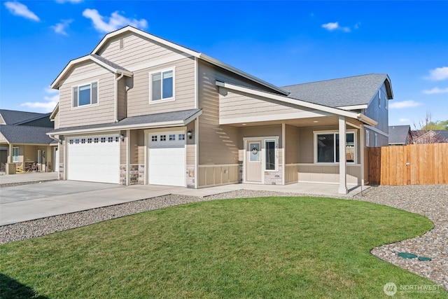 view of front of property with fence, driveway, stone siding, a front yard, and a garage