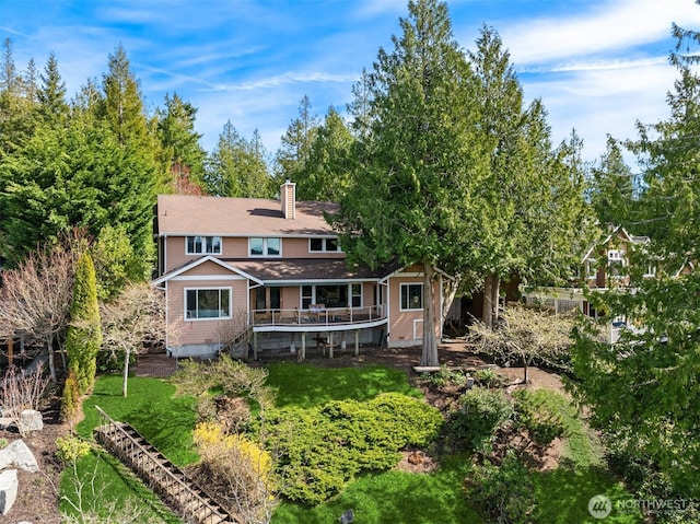 rear view of property featuring a chimney and a deck