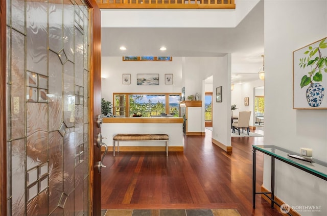 corridor featuring wood finished floors, plenty of natural light, recessed lighting, and baseboards