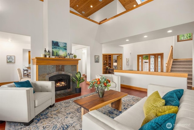 living area with recessed lighting, wood finished floors, high vaulted ceiling, stairs, and a fireplace