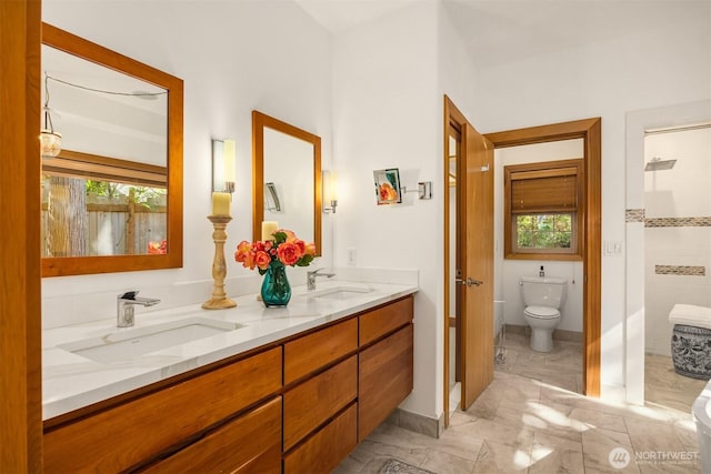 bathroom with toilet, double vanity, and marble finish floors