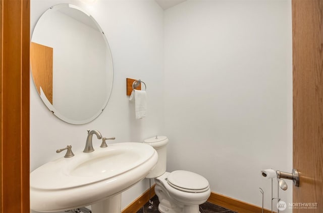 bathroom with a sink, toilet, and baseboards