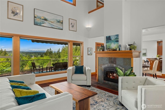 living area with a towering ceiling, wood finished floors, and a tiled fireplace