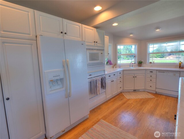 kitchen with light countertops, light wood-type flooring, white appliances, and white cabinetry