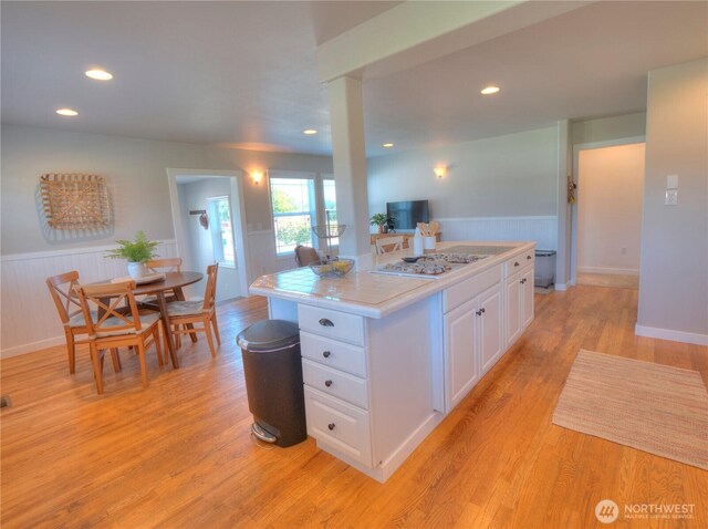 kitchen featuring white cabinetry, white gas stovetop, wainscoting, and light wood finished floors