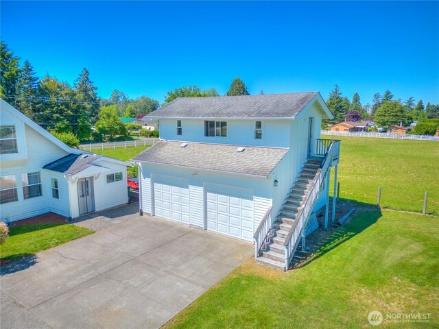 view of front of home with a front lawn, fence, a shingled roof, concrete driveway, and stairway