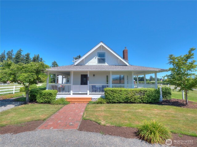 farmhouse featuring fence, covered porch, and a front lawn