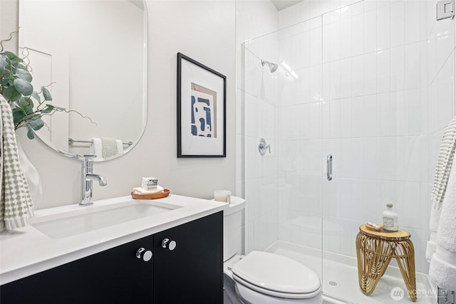 bathroom featuring toilet, vanity, and a stall shower