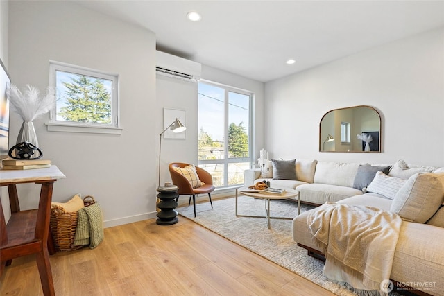 living room with an AC wall unit, baseboards, wood finished floors, and recessed lighting