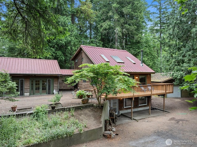 13600 Hillcrest St NW, Poulsbo, WA 98370 - rear view of house with french doors, a wooden deck, a metal roof, and a standing seam roof