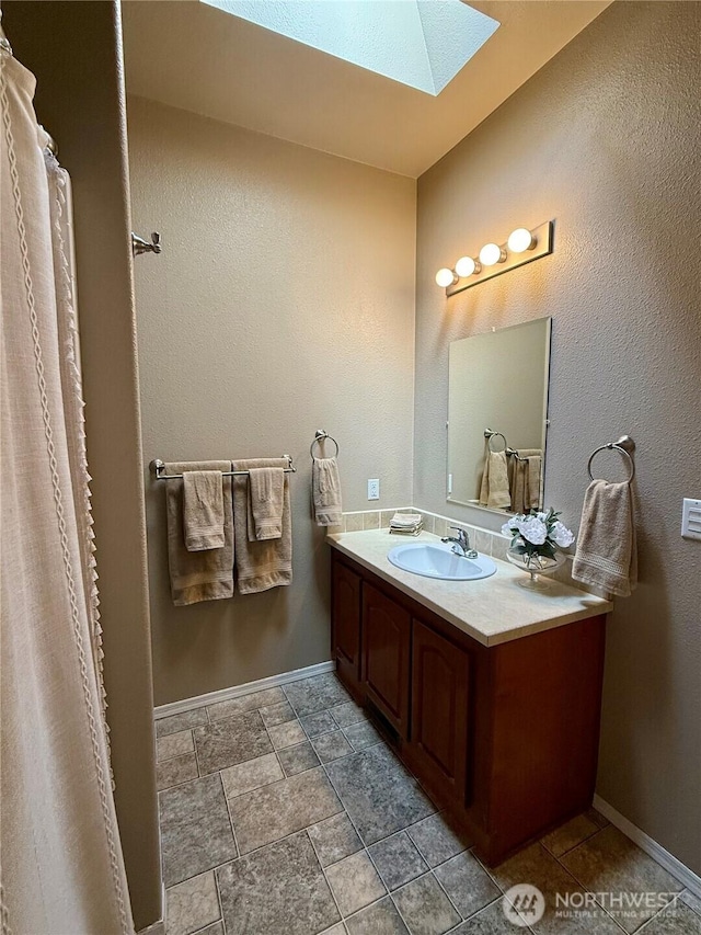 168 Jackson Rd, Orcas Island, WA 98245 - full bathroom with a skylight, vanity, baseboards, and stone finish flooring