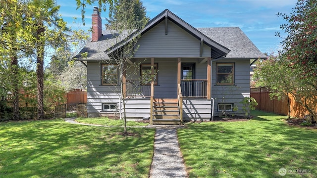 bungalow featuring a porch, a front lawn, a chimney, and fence