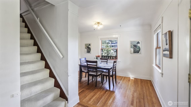 dining room with baseboards, wood finished floors, and stairway