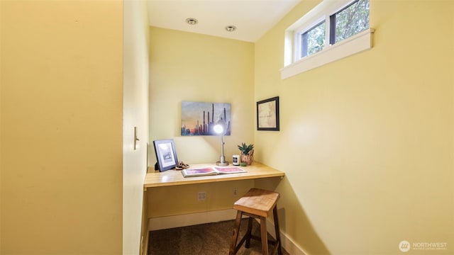 office area with baseboards, dark colored carpet, and built in desk