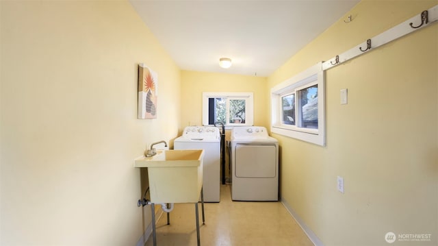 laundry area with washing machine and dryer, baseboards, a sink, and laundry area