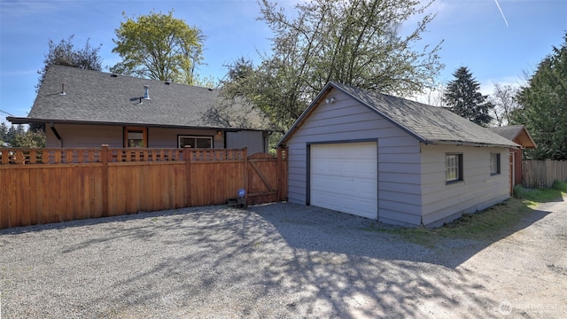 detached garage featuring driveway and fence