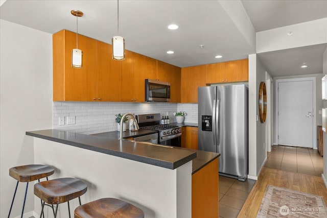 76 Cedar St Unit Ph07, Seattle, WA 98121 - kitchen featuring stainless steel appliances, a peninsula, dark countertops, tasteful backsplash, and brown cabinets