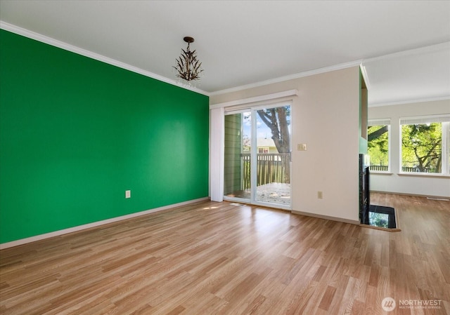 empty room featuring crown molding, wood finished floors, and baseboards