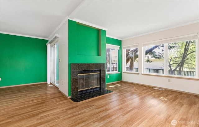 unfurnished living room with baseboards, visible vents, wood finished floors, and a fireplace