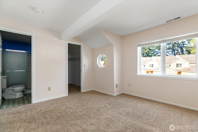 unfurnished bedroom featuring a spacious closet, ensuite bath, carpet flooring, baseboards, and visible vents