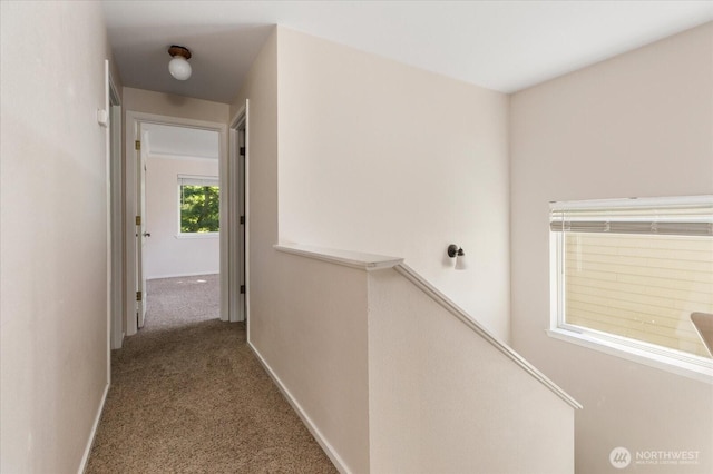 corridor with baseboards, an upstairs landing, and carpet flooring