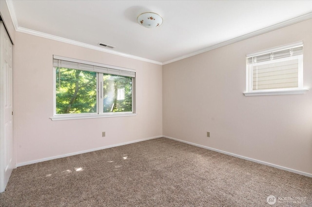 carpeted empty room with baseboards, visible vents, and crown molding