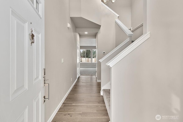 foyer entrance with wood finished floors, baseboards, visible vents, and stairs
