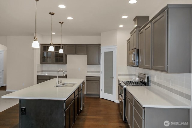 kitchen featuring appliances with stainless steel finishes, dark wood-type flooring, tasteful backsplash, and a sink